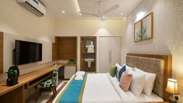 Una habitación de hotel con cama, escritorio, televisor y ventilador de techo.