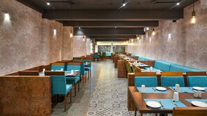 A restaurant with a long counter and booths, featuring patterned tile flooring and wooden furniture. - Time Square Boutique Hotel (Ambalapuzha)
