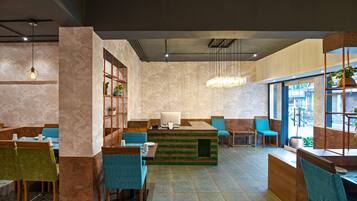 A modern restaurant with a central counter, blue chairs, and a large window.