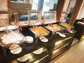 Un bufé con diversos alimentos y utensilios de servicio.