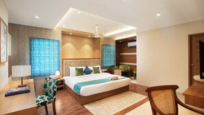 A modern hotel room with a large bed, a desk, a chair, and a bathroom. - Time Square Boutique Hotel (Ambalapuzha)