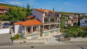 A multi-story residential building with a red-tiled roof, balconies, and a stone facade. - Modern apartment with terrace and fantastic sea view (Crikvenica)