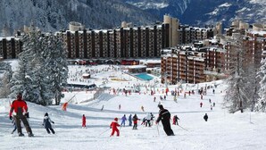 A ski resort with multiple buildings, a ski slope, and a pool area. - 200m from resort center, 4th floor, view ski slopes, swimming pool, balcony, tv, ski locker, 28m² (La Plagne)