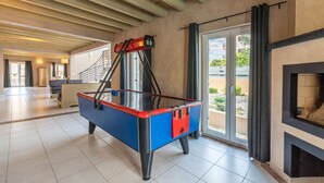 A spacious room with a pool table, a fireplace, and a view through a glass door. - Bellavista in Premantura (Medulin)