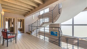 A spacious interior with a wooden floor, a staircase with metal railings, and large windows providing natural light. - Bellavista in Premantura (Medulin)
