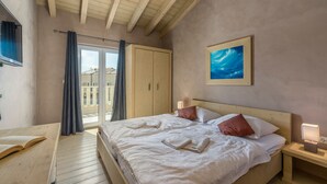 A bedroom with a large bed, a wooden headboard, a painting on the wall, and a window with curtains. - Bellavista in Premantura (Medulin)