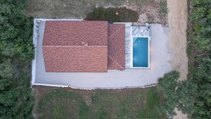 Vista aérea de una casa con techo de tejas, piscina y un pequeño patio.
