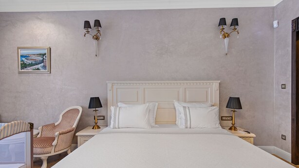 A hotel room with a large bed, two bedside tables with lamps, a chair, and a wall-mounted picture. - Carolus Dalmatia in Vodice (Vodice)