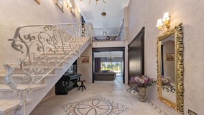 A grand staircase with ornate metal railings, a large mirror with a gold frame, and a patterned floor rug. - Carolus Dalmatia in Vodice (Vodice)