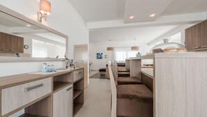 A modern kitchen with a wooden countertop, a large mirror, and a seating area with a bench. - Dalmacija VII in Suko an (Sukosan)