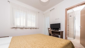 A hotel room with a bed, a desk with a computer, a TV, and a shower area. - Dalmacija VII in Suko an (Sukosan)