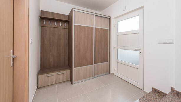 A room with a wooden wardrobe, a white door with frosted glass panels, and a tiled floor. - Dalmacija VII in Suko an (Sukosan)