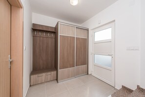 A room with a wooden wardrobe, a white door with frosted glass panels, and a tiled floor. - Dalmacija VII in Suko an (Sukosan)
