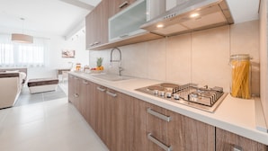 A modern kitchen with wooden cabinets, a stainless steel stove, and a large window. - Dalmacija VII in Suko an (Sukosan)
