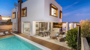 Una casa moderna de dos pisos con piscina, zona de estar al aire libre y un amplio ventanal que da a un patio.