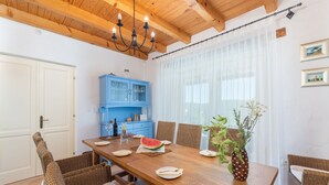 A dining area with a wooden table, wicker chairs, a blue cabinet, and a chandelier. - Sienna in Buzet With 4 Bedrooms and 2 Bathrooms (Buzet)