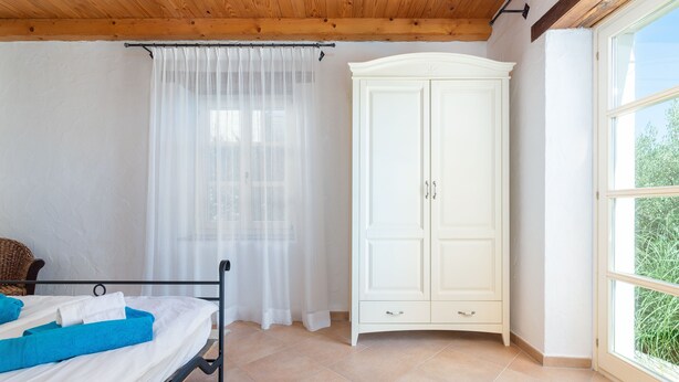 A bedroom with a bed, white curtains, a white wardrobe, and a window with a view. - Sienna in Buzet With 4 Bedrooms and 2 Bathrooms (Buzet)