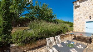 An outdoor patio with a stone wall, a table set for four, and a stone building in the background. - Sienna in Buzet With 4 Bedrooms and 2 Bathrooms (Buzet)