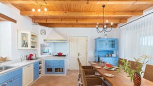 A kitchen with blue cabinets, a wooden ceiling, and a dining area with wicker chairs. - Sienna in Buzet With 4 Bedrooms and 2 Bathrooms (Buzet)