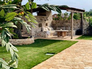 A stone patio with a stone wall, a wooden pergola, and a seating area with a table and chairs. - Bofina in Kanfanar With 4 Bedrooms and 2 Bathrooms (Kanfanar)