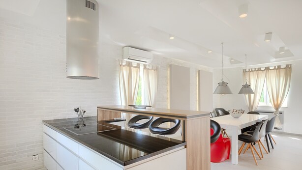A modern kitchen with a central island, white cabinetry, and a dining area with a table and chairs.