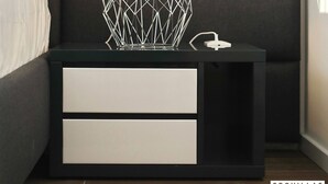 A modern bedroom with a dark upholstered headboard, a geometric wire lamp, and a bedside table with two drawers. - K2 in Kraj Pa man Island (Pasman)