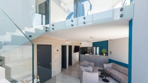 A modern interior with a staircase, a living area with a sofa and chairs, and a kitchen area. - M8 in Vir With 2 Bedrooms and 2 Bathrooms (Vir)