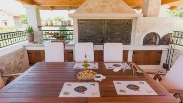 A wooden dining table with a bottle of olive oil, a bowl of nuts, and a menu.