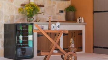 A kitchen with a wooden cart, a refrigerator, and a stone wall.