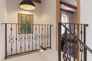 Un escalier orné de rampes noires, un tableau accroché au mur et un luminaire suspendu au plafond.