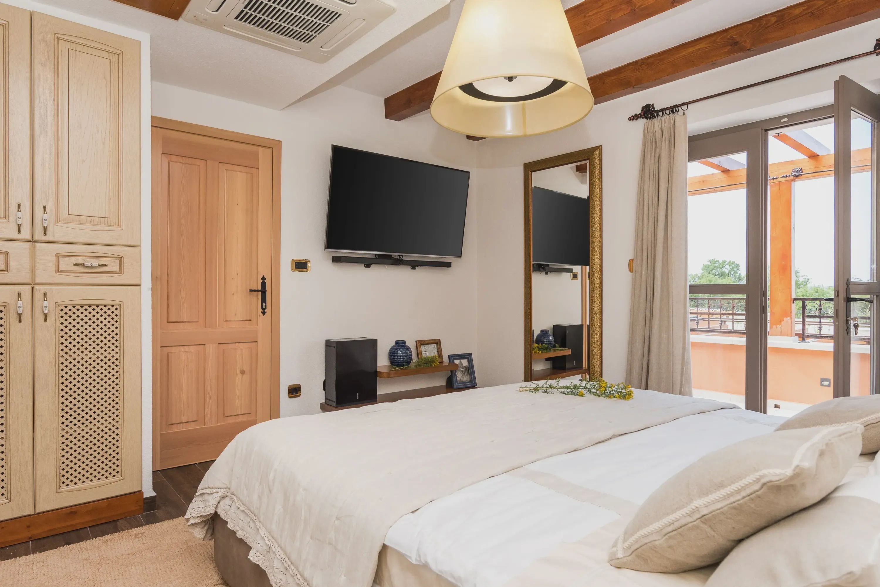 Une chambre avec un lit, une télévision, un grand miroir et un balcon avec vue.