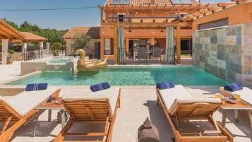 A pool area with lounge chairs, a swan float, and a pergola.
