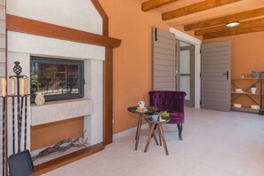 A cozy room with a fireplace, a purple chair, and a small table with a cup and saucer.