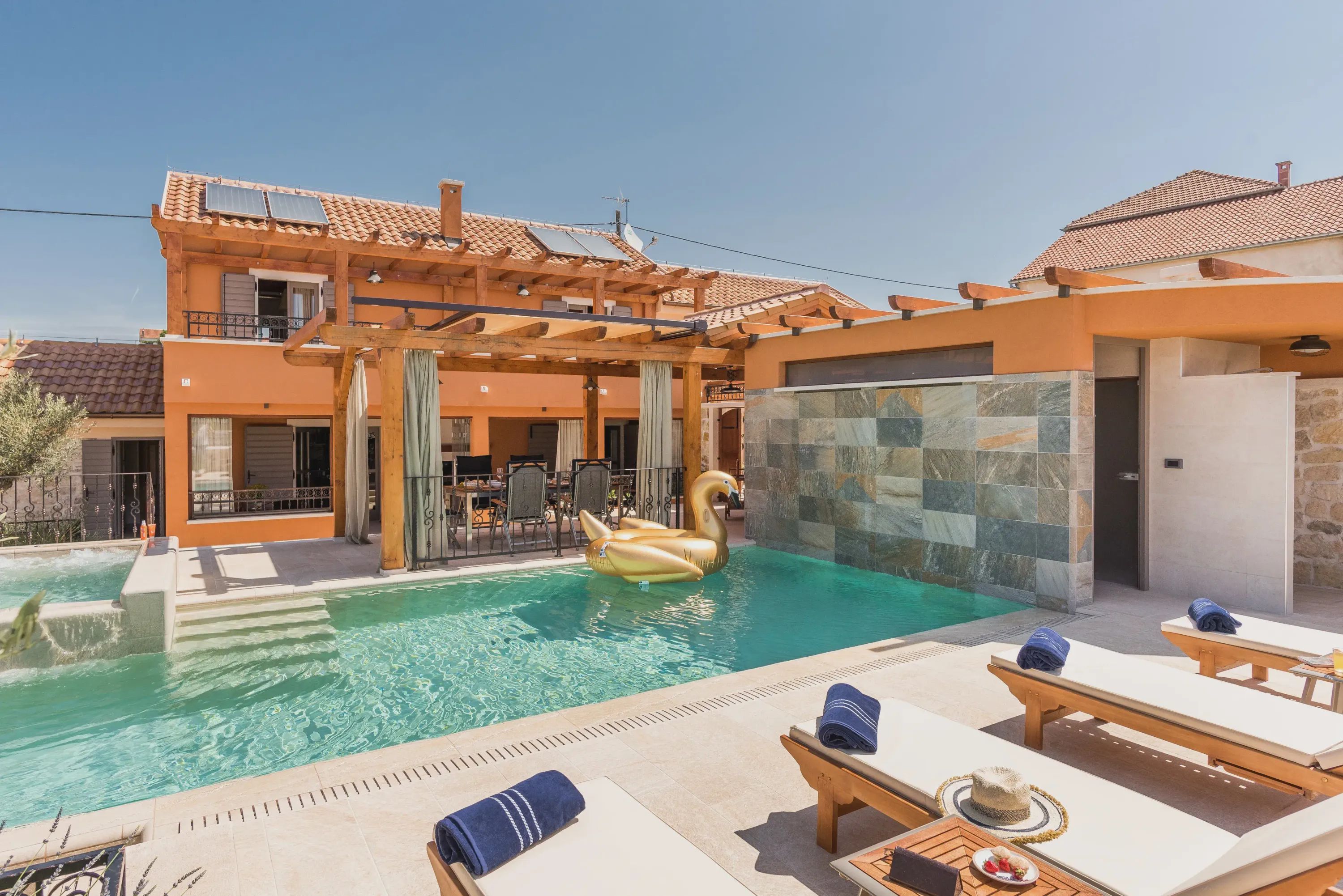A swimming pool with a swan float, lounge chairs, and a covered patio area.