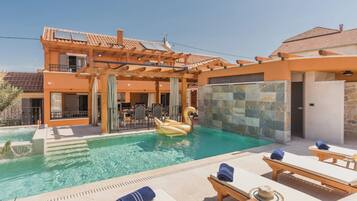 A swimming pool with a swan float, lounge chairs, and a covered patio area.
