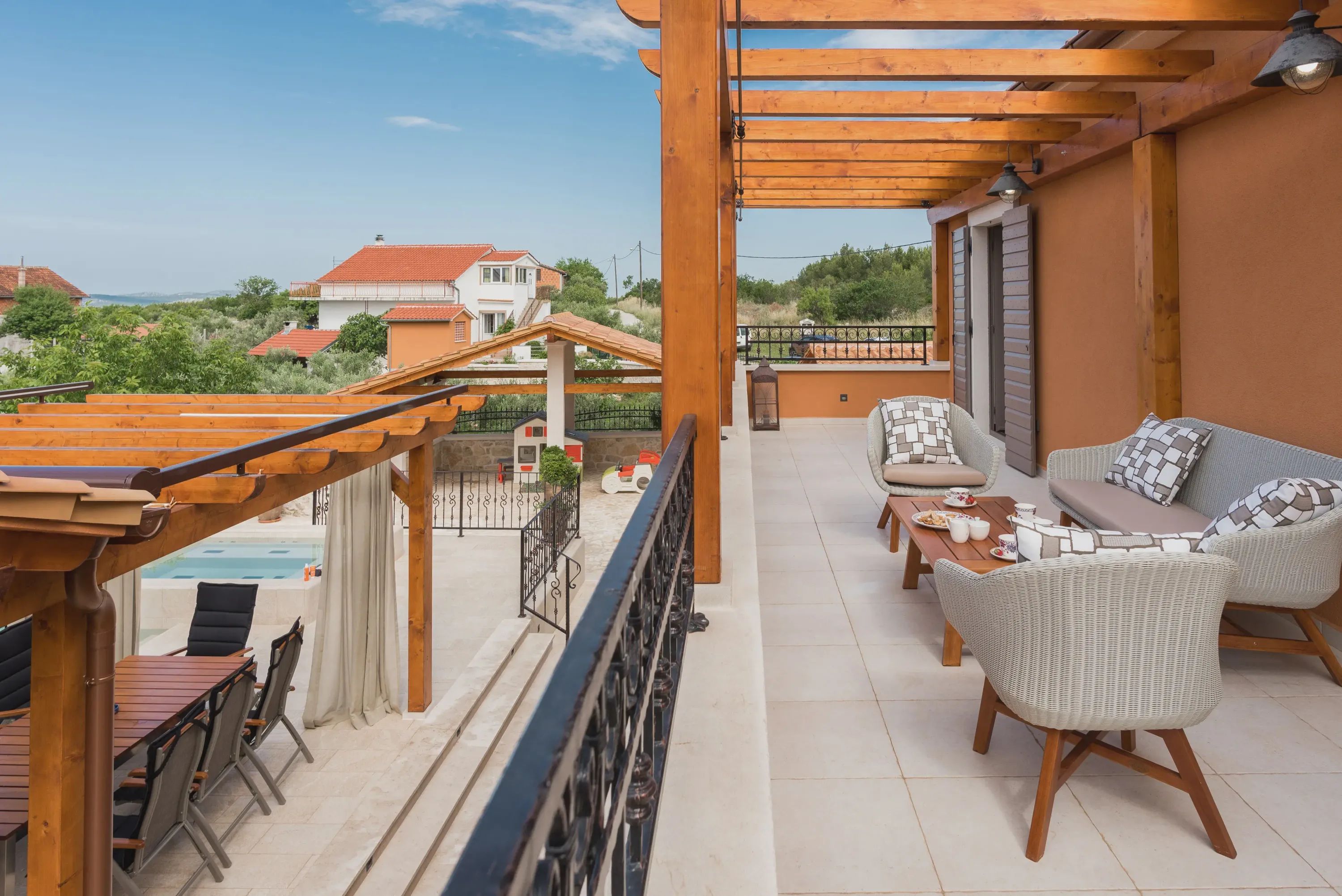 A balcony with outdoor furniture, a pool, and a view of houses in the background.