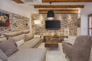 Sala de estar com parede de pedra, televisão de tela plana, mesa de centro de madeira e sofá.