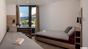 A modern bedroom with two beds, a wooden desk, and a view of mountains. - Soul Stella in Kor ula (Korčula)