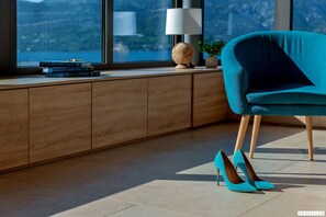 A modern room with a view of a cityscape, a teal chair, a pair of high heels, and a stack of books on a wooden console table. - Soul Stella in Kor ula (Korčula)