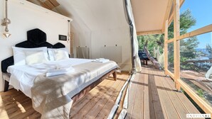A bedroom with a large bed, wooden flooring, and a view of the outdoors. - Treehouse in Murter With 1 Bedrooms and 1 Bathrooms (Tisno)