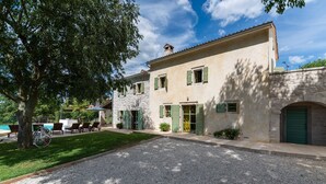 A two-story building with a stone facade, green shutters, and a gravel driveway. - Zvonar in Rakotule With 3 Bedrooms and 3 Bathrooms (Karojba)