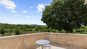 A stone-walled outdoor patio with two round tables and metal chairs, overlooking a lush landscape. - Zvonar in Rakotule With 3 Bedrooms and 3 Bathrooms (Karojba)