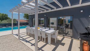 A modern outdoor patio with a pool, white furniture, and a pergola structure. - Luna in Pomer With 6 Bedrooms and 6 Bathrooms (Medulin)