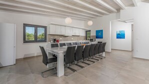 A modern kitchen with a large island, white cabinetry, and black chairs. There are two pendant lights above the island. - Luna in Pomer With 6 Bedrooms and 6 Bathrooms (Medulin)