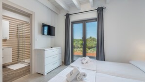 A hotel room with a bed, a TV, a bathroom with a shower, and a view of the outdoors. - Luna in Pomer With 6 Bedrooms and 6 Bathrooms (Medulin)