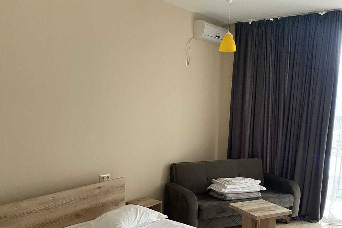 Una habitación de hotel con cama, una silla, una mesita y una ventana con cortinas.
