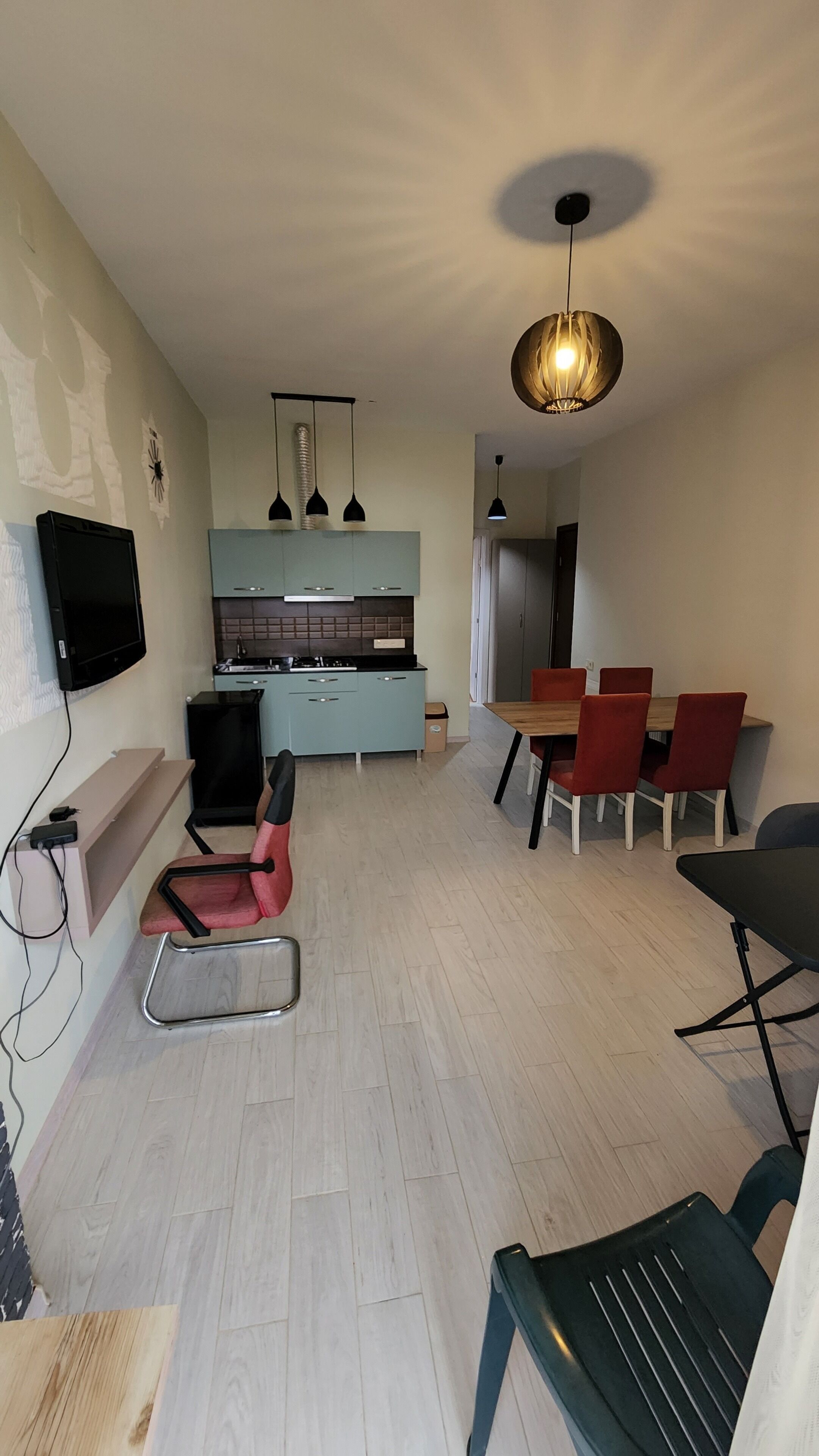 Ein modernes Wohnzimmer mit Essbereich, hellblauen Schränken, einem Flachbildfernseher und einer Deckenleuchte.