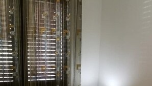 Une chambre à coucher avec un lit, une table de chevet, une lampe et une fenêtre avec des rideaux.