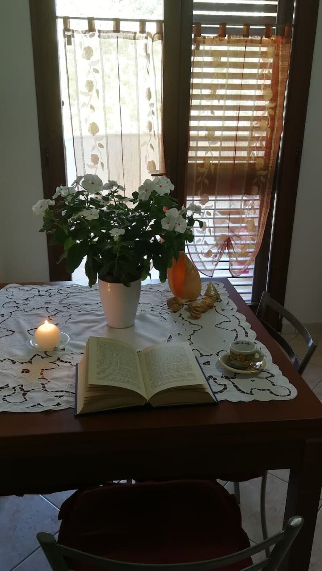 A table with a book, a candle, and a potted plant.