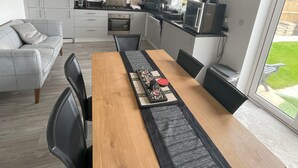 A modern kitchen with white cabinets, a dining table with black chairs, and a large window.
